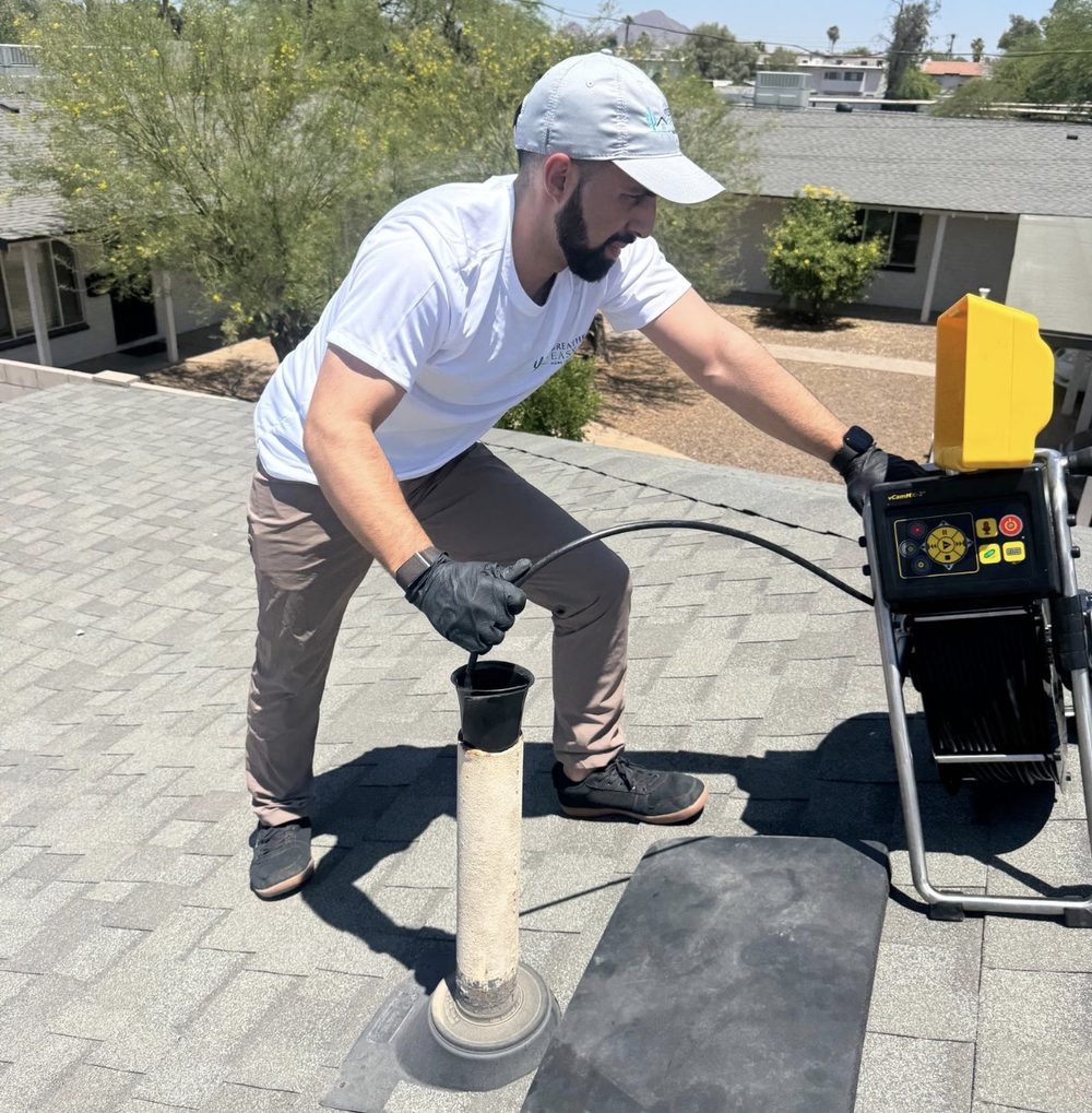 Konnor Kirkwood running a sewer scope on a rooftop vent stack